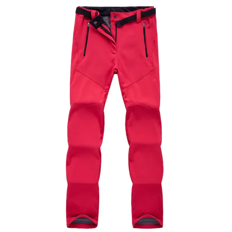 Red outdoor softshell pants with black zipper pockets and adjustable waist straps on white background