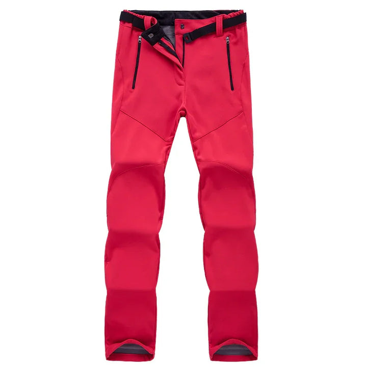 Red outdoor softshell pants with black zipper pockets and adjustable waist straps on white background