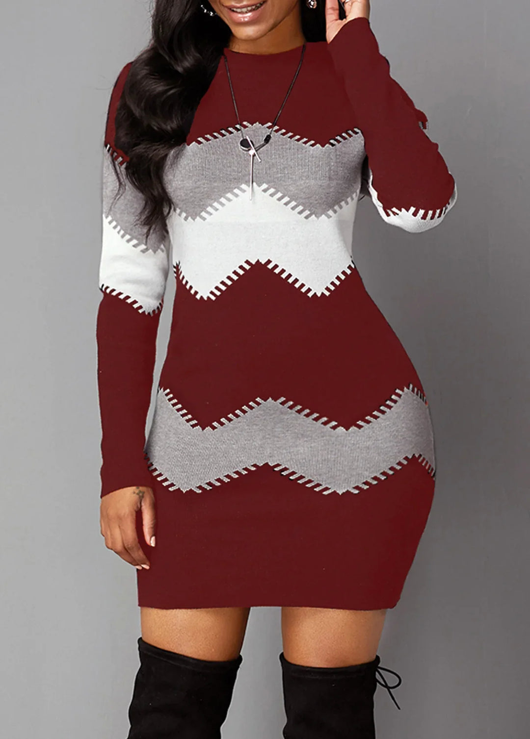 Woman wearing a maroon knit bodycon dress with grey and white zigzag patterns and black knee-high boots