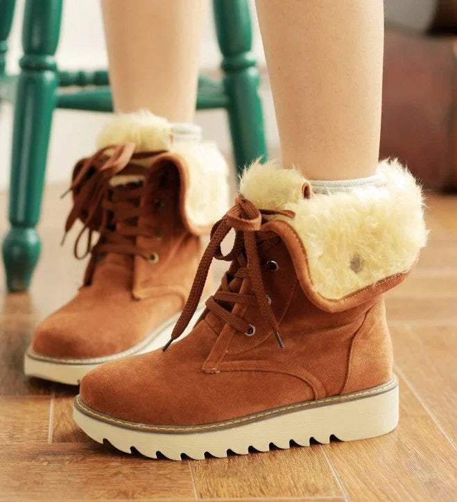 Brown suede winter boots with cream fur lining and thick white rubber soles on wooden floor