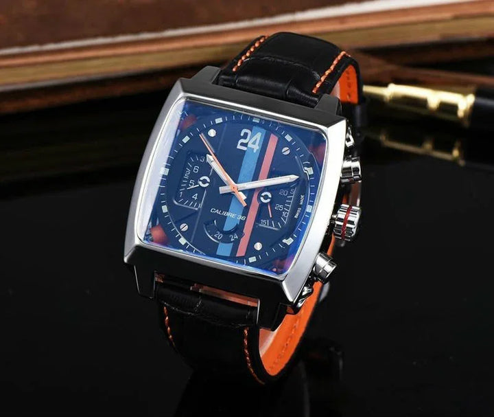 square wristwatch with black dial, blue and orange stripes, black leather strap with orange stitching