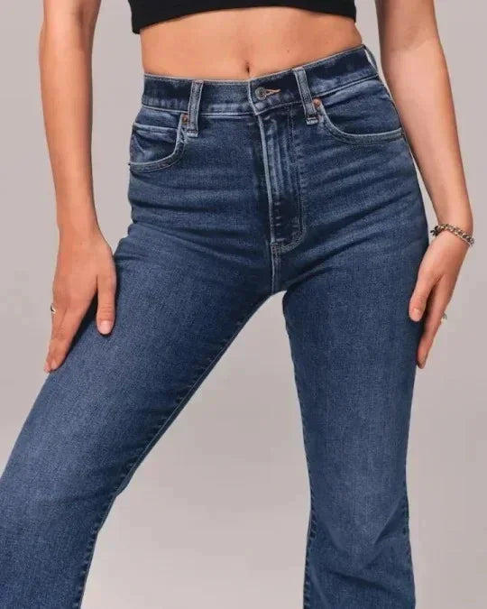 Close-up of mid-rise dark blue denim jeans worn by a person with hands resting on hips