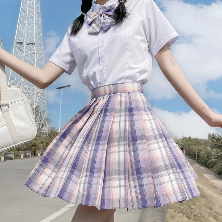 Young woman in white blouse and purple plaid pleated skirt with bow tie, carrying white bag outdoors