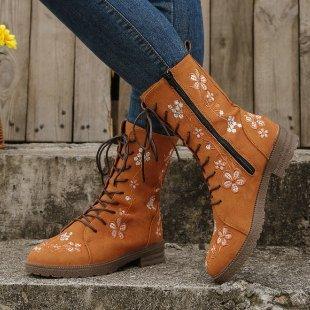Tan lace-up boots with floral embroidery worn with blue jeans on outdoor stone steps