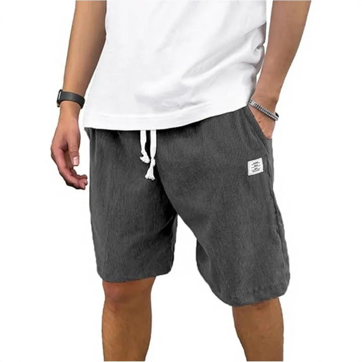 Man wearing casual black shorts with white drawstring and a white t-shirt, hands in pockets