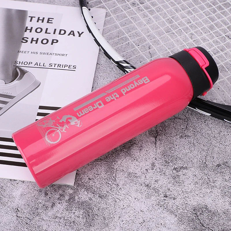 Pink sports water bottle with 'Beyond the Dream' text, on a badminton racket and magazine