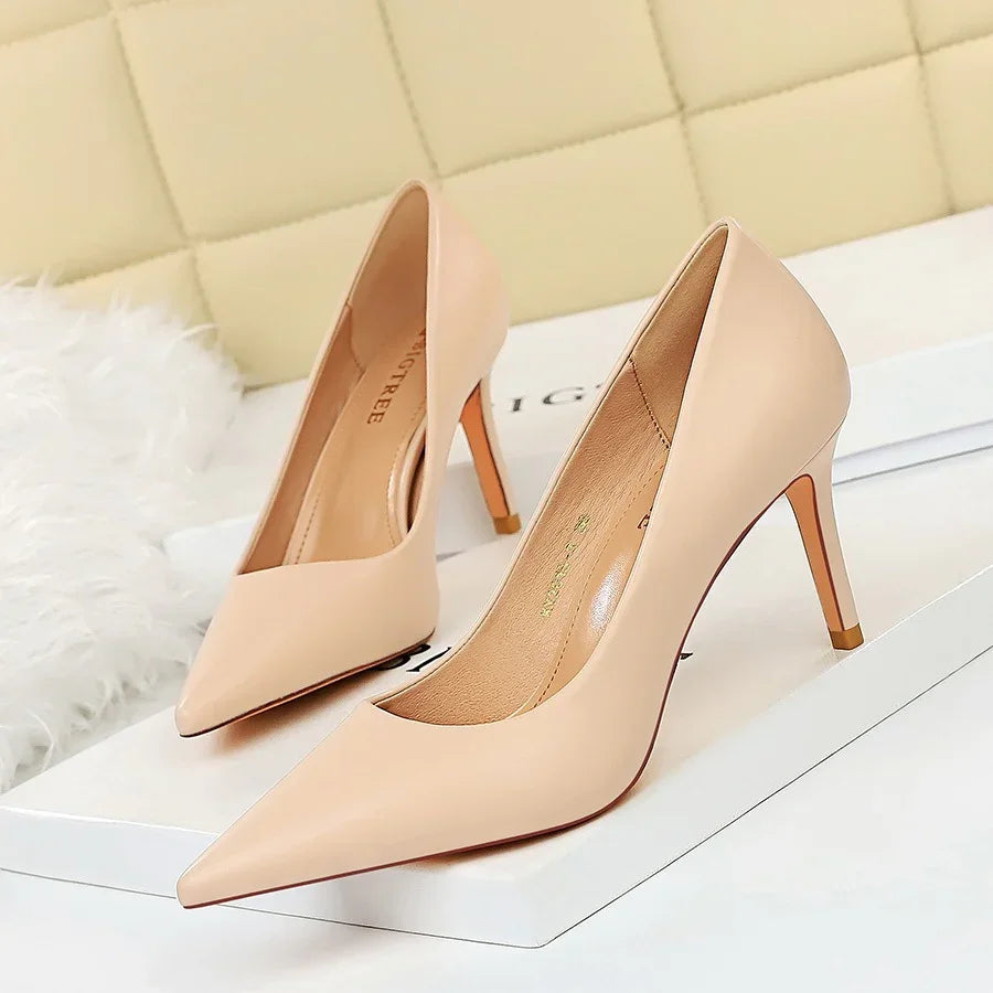 Pair of elegant nude pointed-toe high heel pumps displayed on white boxes
