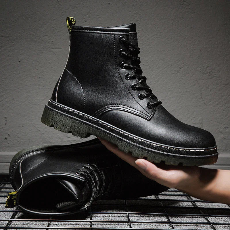 Black leather combat boots with thick sole, hand holding one boot, industrial background