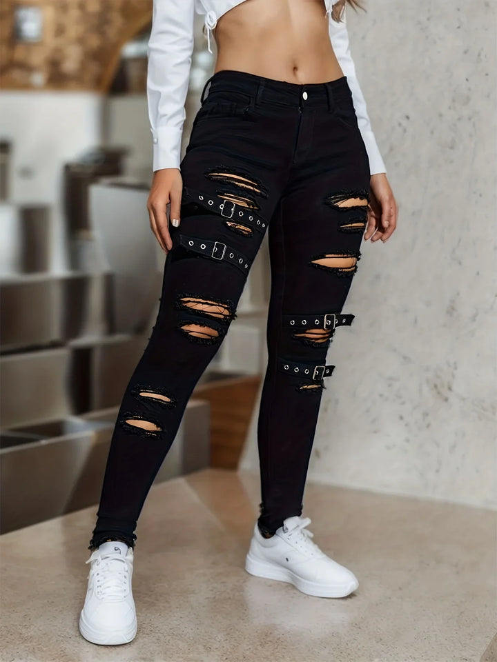 Woman wearing black ripped skinny jeans with buckle straps and white sneakers in modern interior