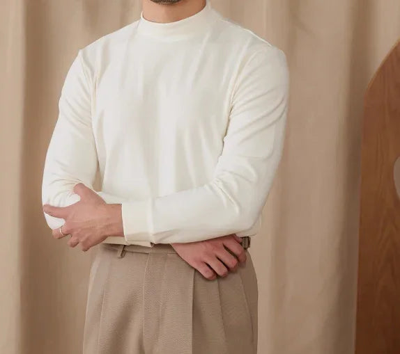 Man wearing cream-colored long sleeve shirt and beige high-waist pants with neutral background