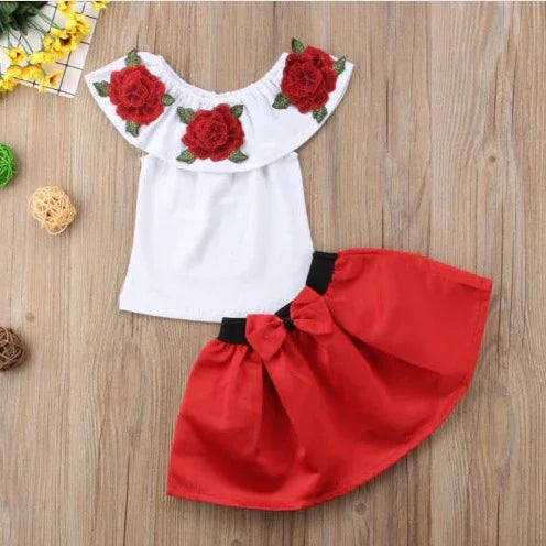 White sleeveless top with red rose embroidery paired with a red skirt with a black waistband and bow