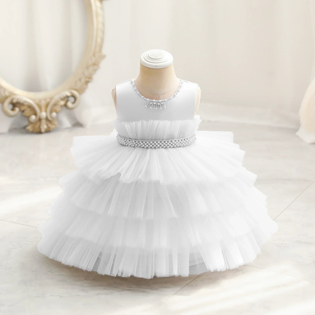 White sleeveless baby dress with layered tulle skirt and pearl details on mannequin