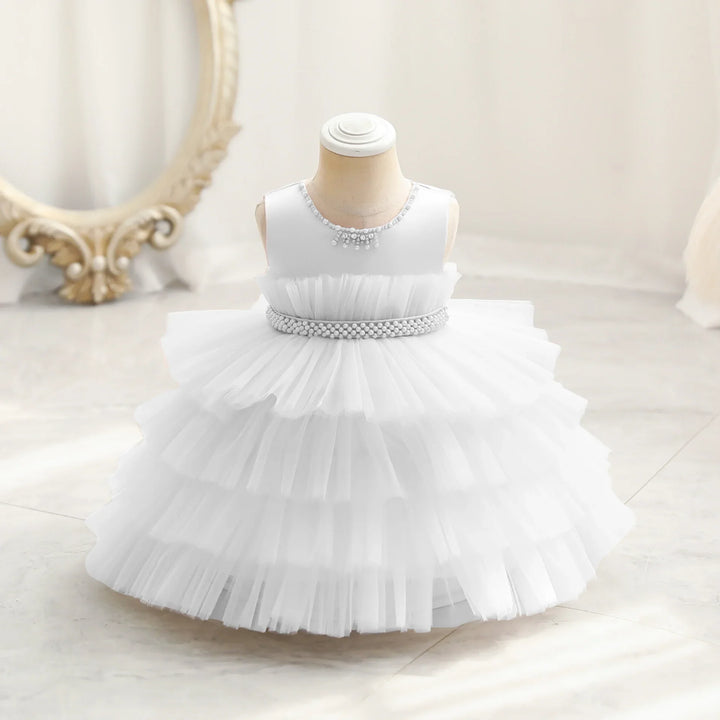White sleeveless baby dress with layered tulle skirt and pearl details on mannequin