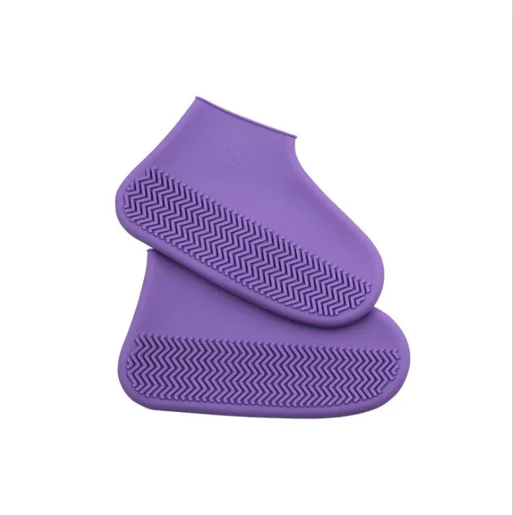 Pair of purple silicone shoe covers with textured non-slip soles on white background