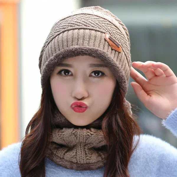 Young woman wearing brown knitted winter hat and matching scarf making playful face outdoors