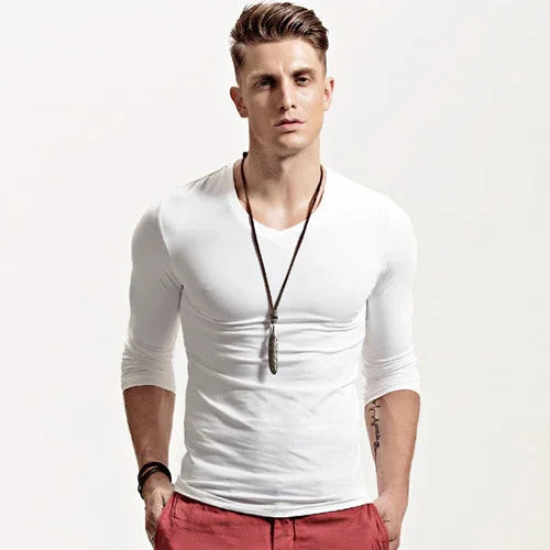 Young man wearing fitted white long-sleeve shirt, red pants, and pendant necklace on white background