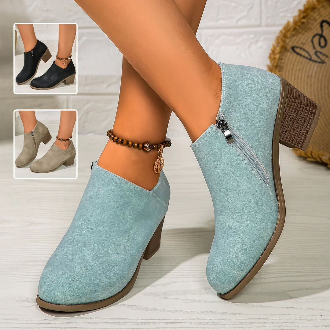 Women's ankle boots in light blue suede with block heel and side zipper, styled with beaded ankle bracelet