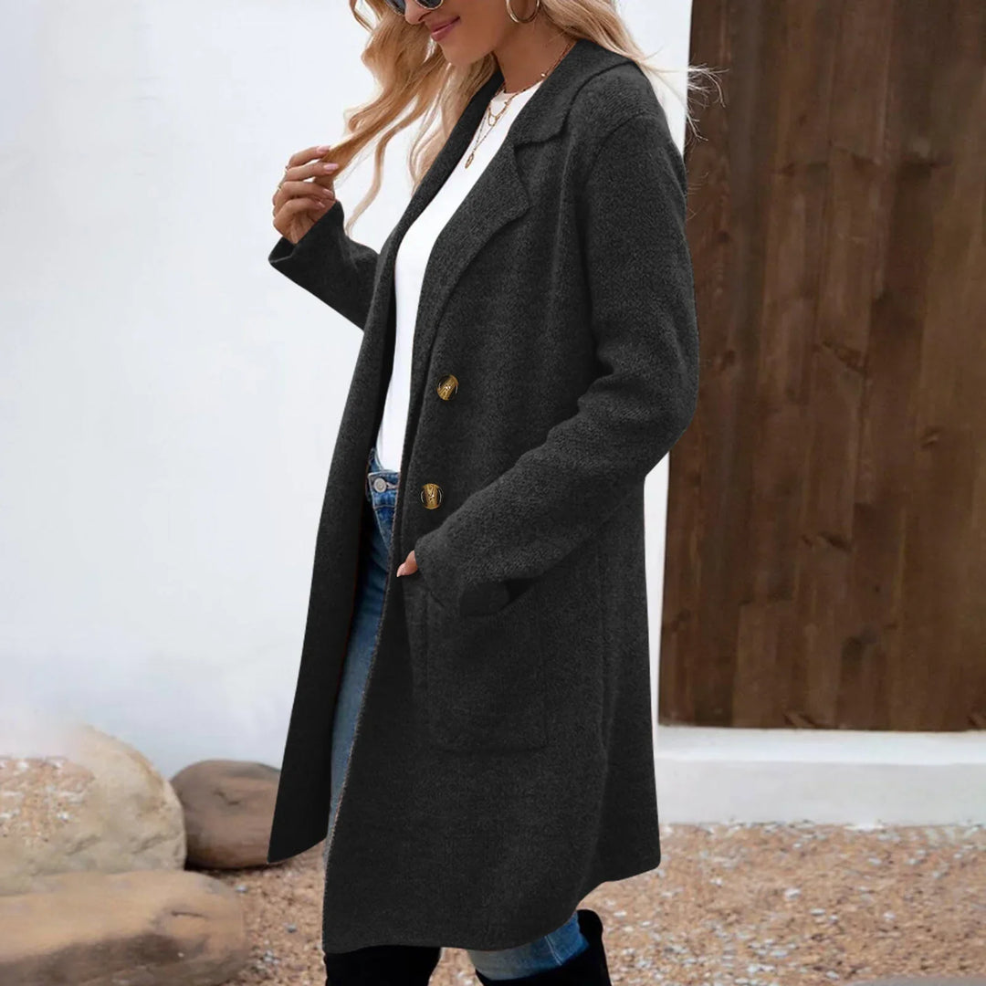 Woman wearing long dark gray buttoned wool coat with pockets over white top and jeans