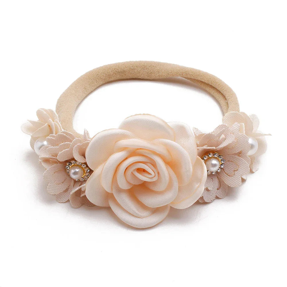 Beige floral baby headband with fabric rose and pearl rhinestone accents on white background