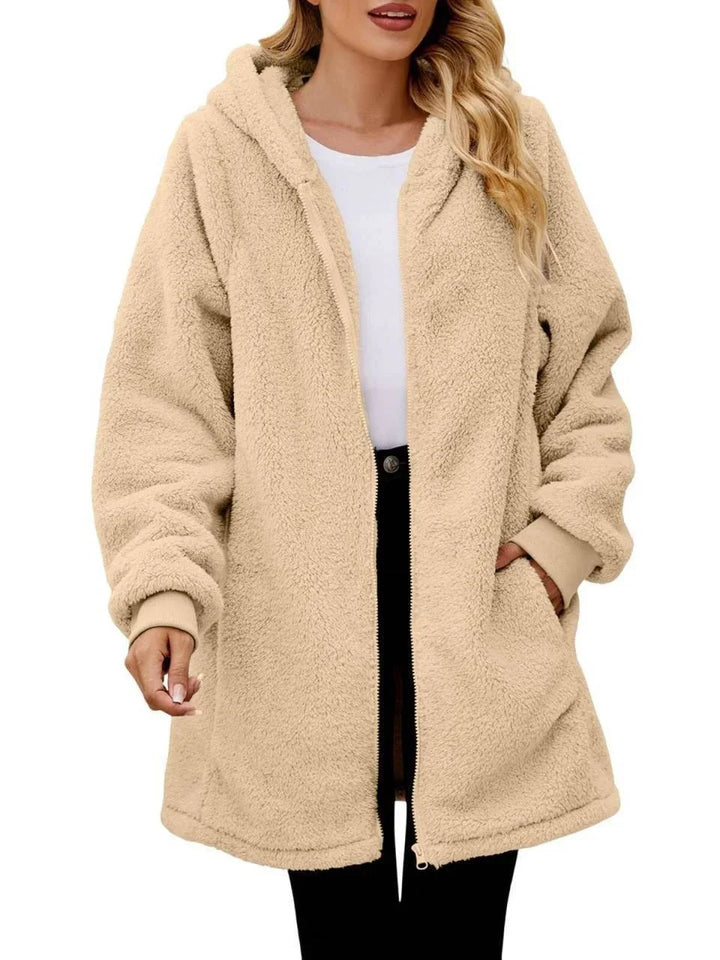 Woman wearing beige oversized sherpa fleece hoodie jacket with front zipper and pockets