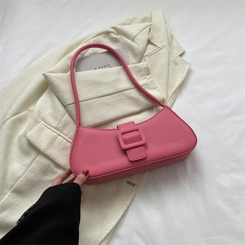 Pink leather shoulder bag with buckle detail on cream blazer background