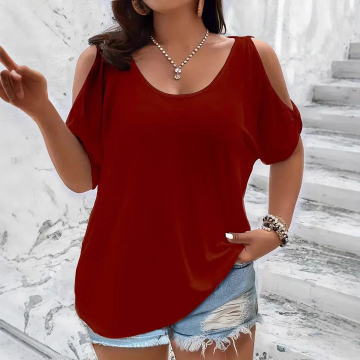 Woman wearing red cold shoulder top and distressed denim shorts against marble stairs background