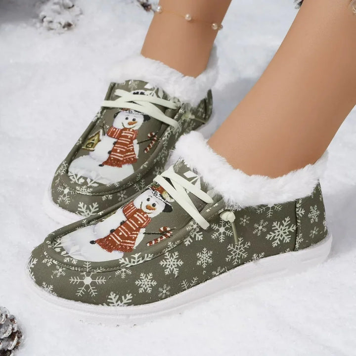 Fuzzy winter slippers with snowman and snowflake design, worn on snow-covered ground