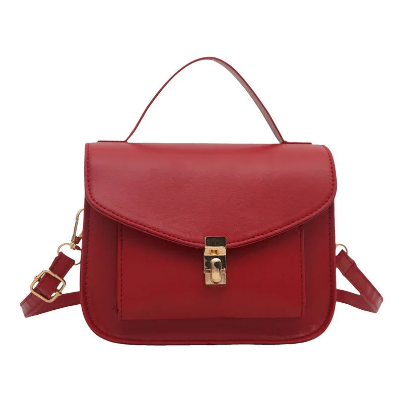 Red leather crossbody bag with gold clasp and adjustable strap on white background