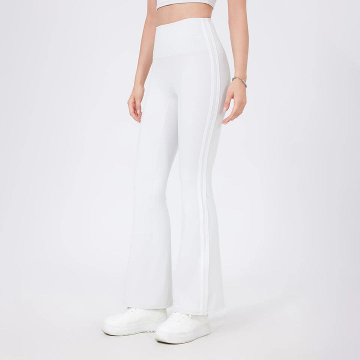 Woman wearing white high-waisted flare leggings with side stripes and white sneakers