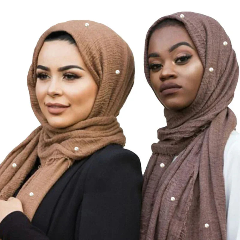Two women wearing textured pearl-embellished hijabs in brown and mauve shades with stylish makeup