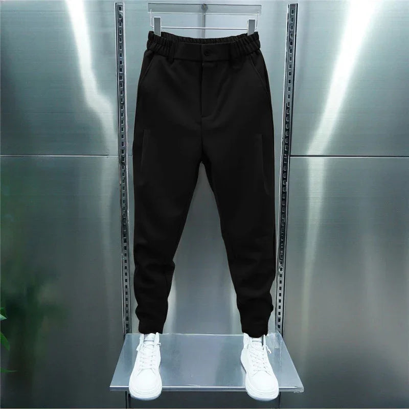 Black tapered jogger pants with elastic waistband displayed on mannequin with white high-top sneakers
