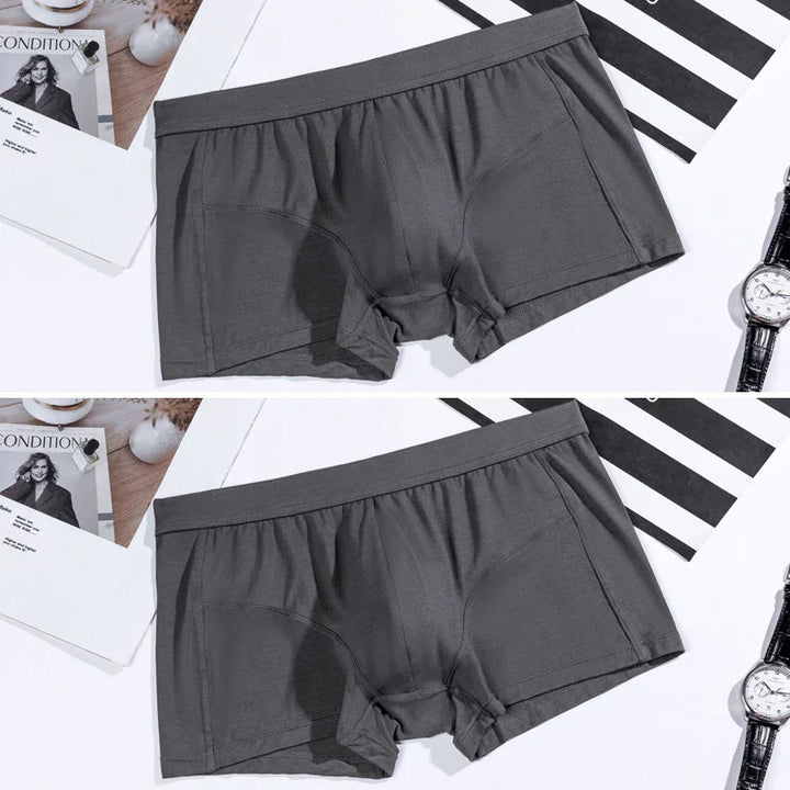 Gray men's boxer briefs laid flat on white surface with watch and magazine nearby