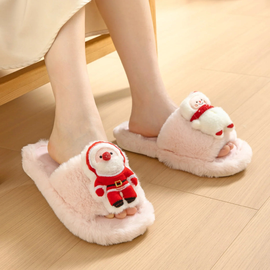 Feet wearing pink fuzzy slippers with plush Santa Claus and snowman decorations on wooden floor