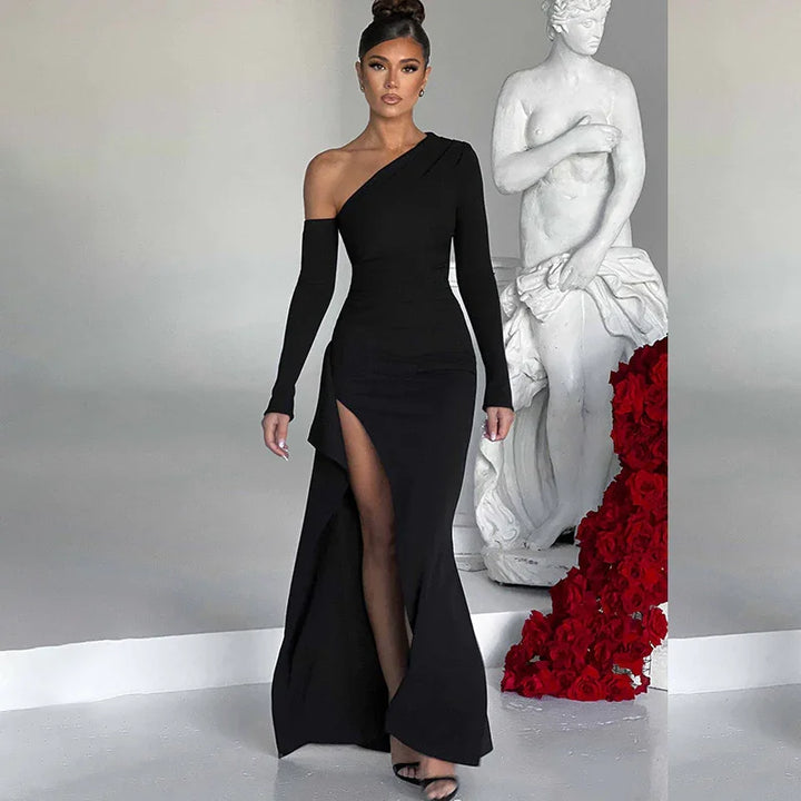 Woman in elegant black one-shoulder gown with thigh slit posing by white statue and red roses