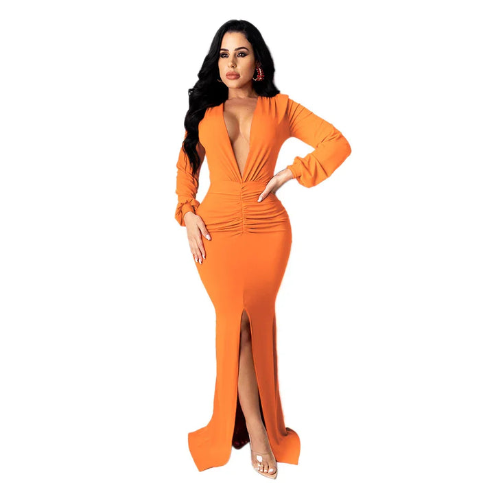 Woman wearing long orange deep V-neck ruched maxi dress with front slit and long sleeves