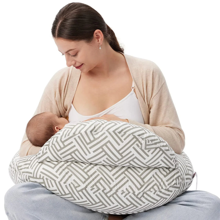 Mother breastfeeding baby using a gray and white patterned nursing pillow on lap