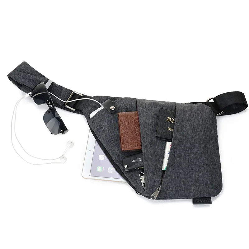 dark gray crossbody sling bag with sunglasses, earphones, tablet, wallet, car keys, and passport on white background