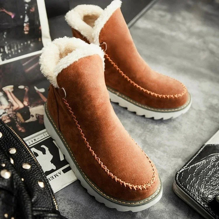 Brown suede winter boots with white fur lining and thick white soles on a gray surface