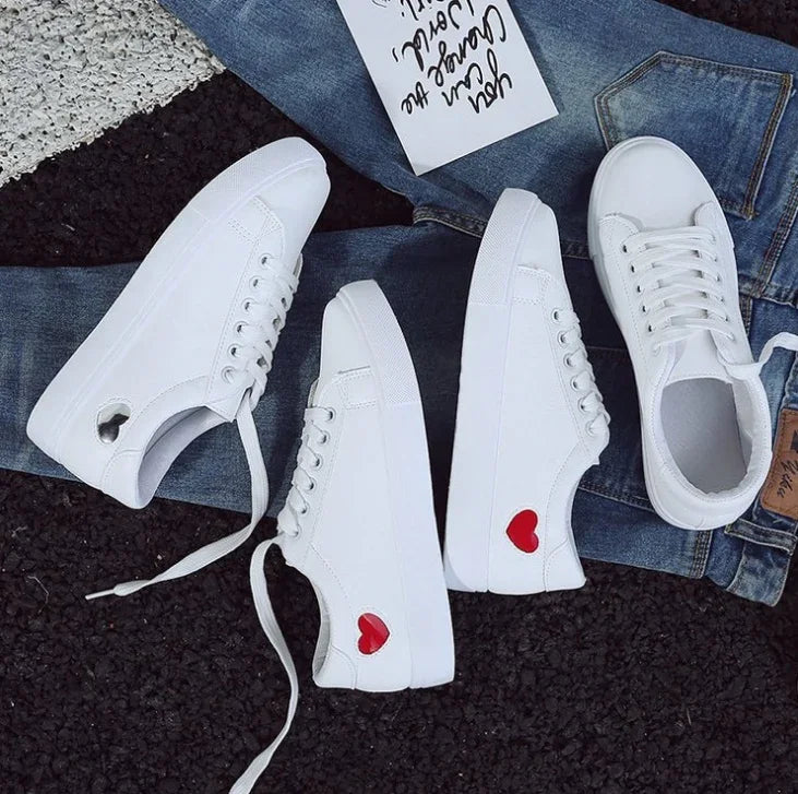 White casual sneakers with red heart detail on denim jeans and handwritten note background