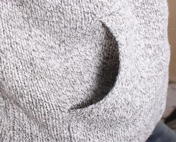 Close-up of a gray and white knitted fabric sweater with a small opening detail