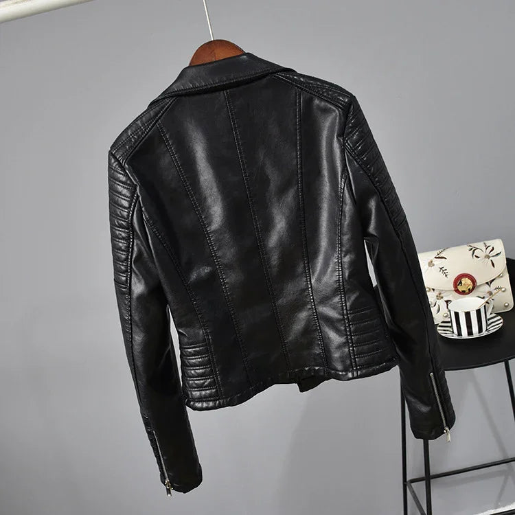 Black faux leather biker jacket hanging on wooden hanger with quilted sleeve details
