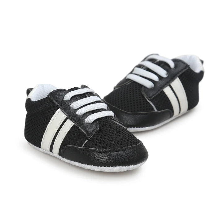 Black and white baby sneakers with mesh fabric and white laces on white background