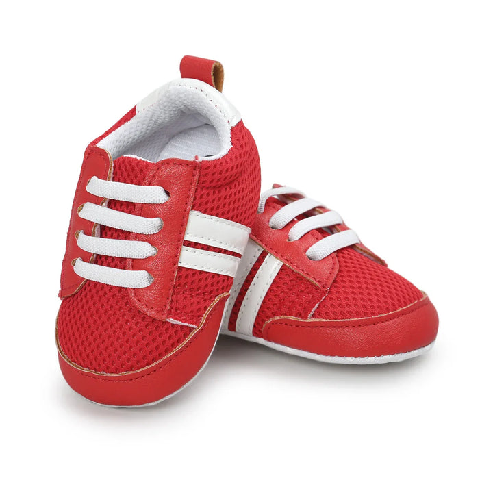 Red and white baby sneakers with mesh fabric and elastic laces on a white background