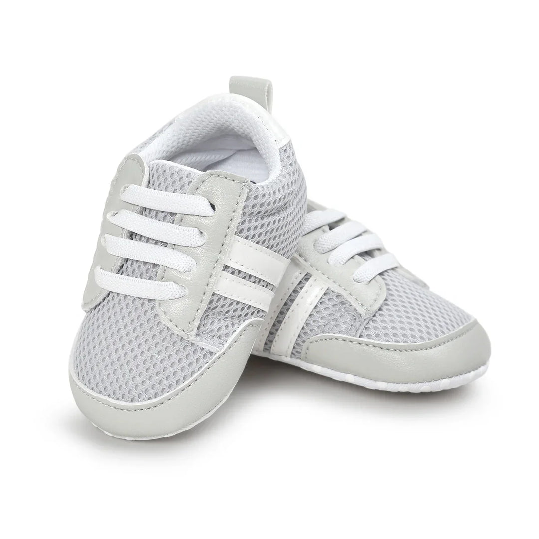 Pair of gray and white baby shoes with mesh fabric and laces on white background