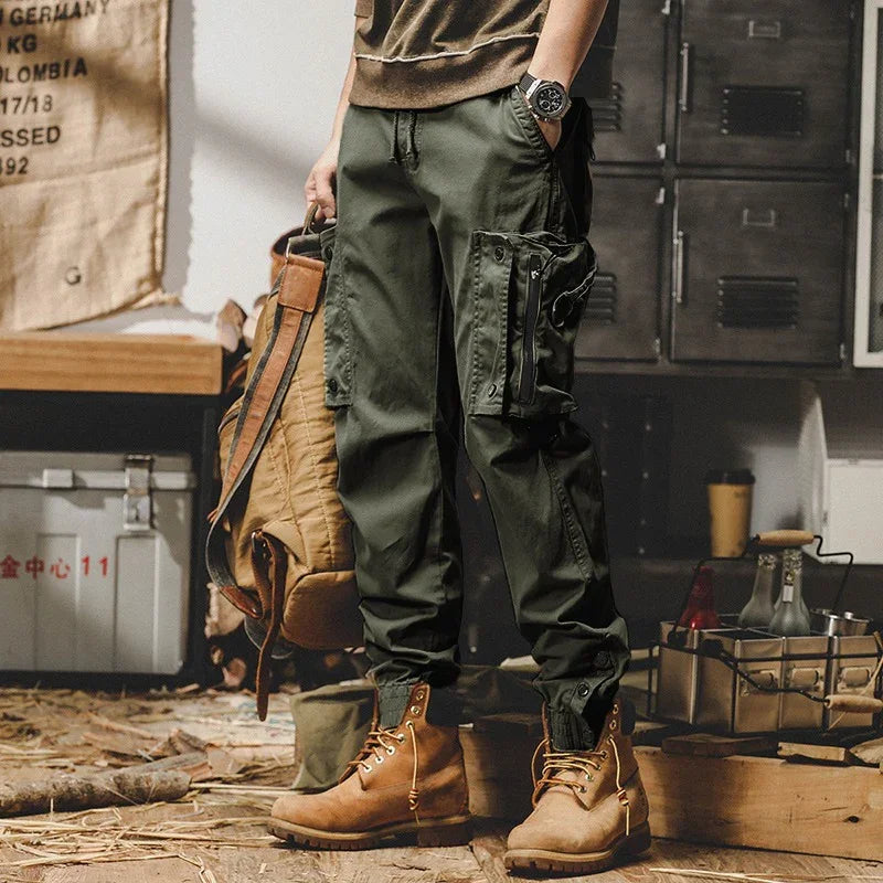 Man wearing olive green cargo pants and brown boots in rustic indoor setting with wooden floor
