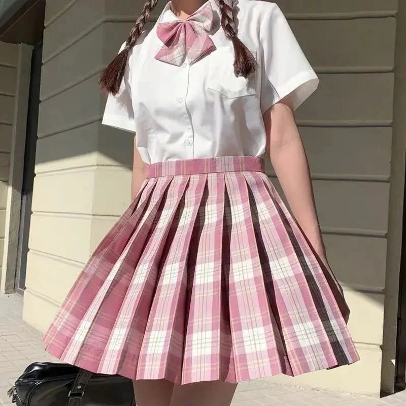 Person wearing white short-sleeve shirt with pink plaid bow and matching pleated skirt outdoors