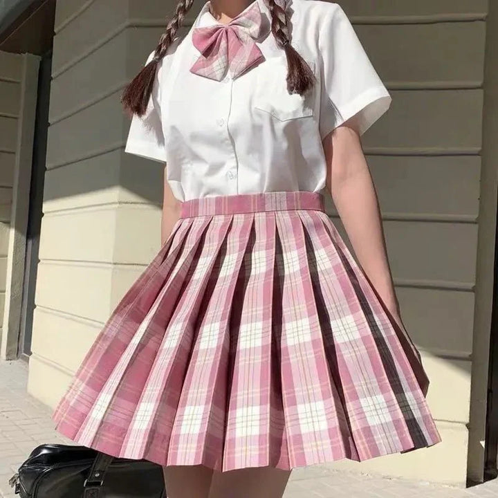 Person wearing white short-sleeve shirt with pink plaid bow and matching pleated skirt outdoors