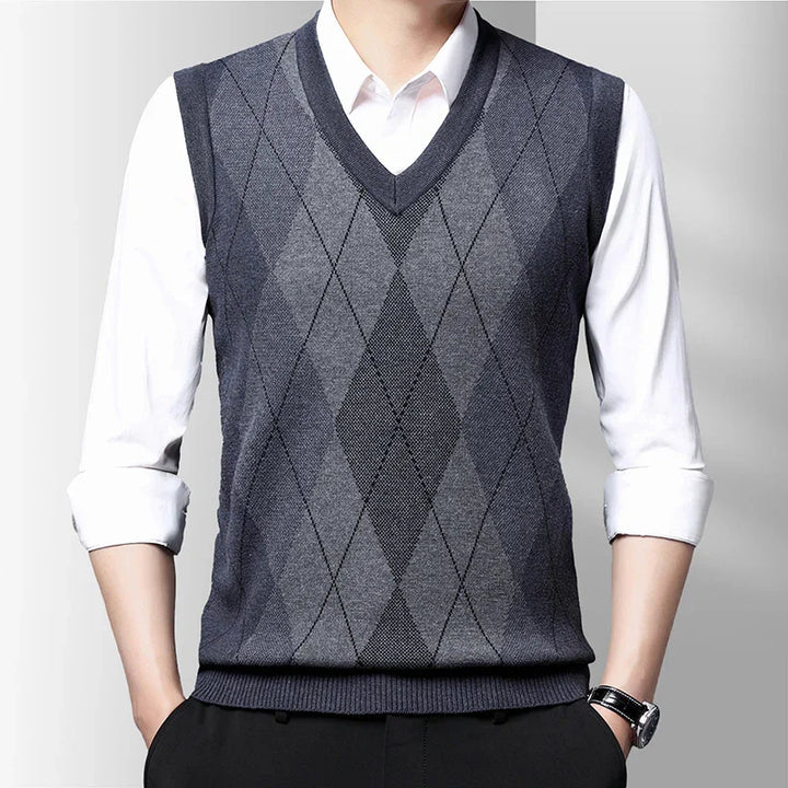 Men's sleeveless argyle sweater vest in shades of gray over white shirt with rolled sleeves