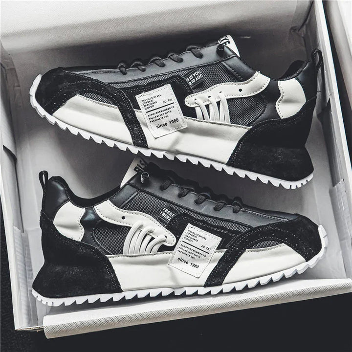 Pair of black and white casual sneakers with mesh and leather details in a shoebox