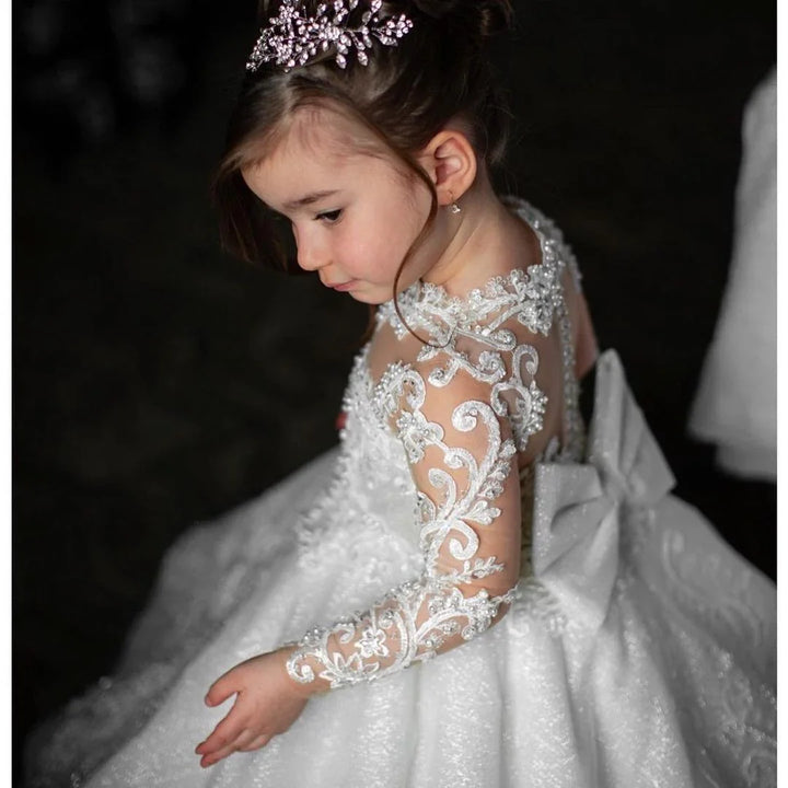 Young girl in a white lace dress with floral embroidery and a jeweled tiara